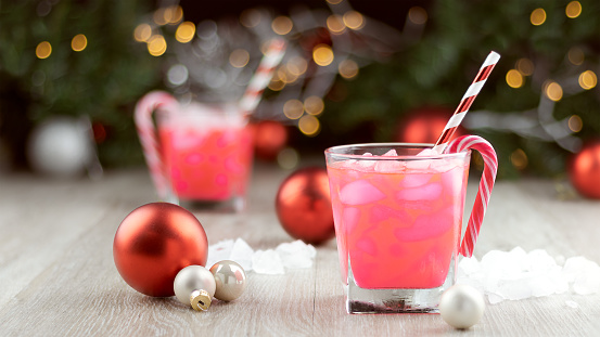 Two christmas party drinks with ice, straws and candy canes and sweets, copy space