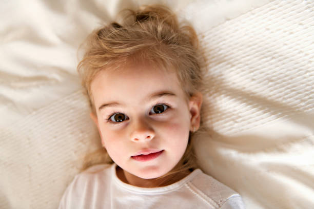 A young daughter two years old relaxing in bed, positive feelings