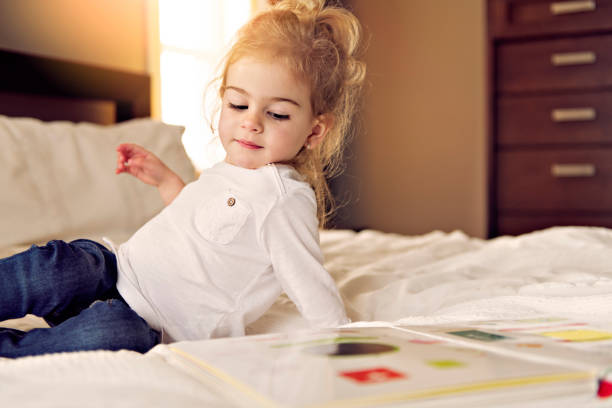istock Little cute girl reading book on bed 1078508676