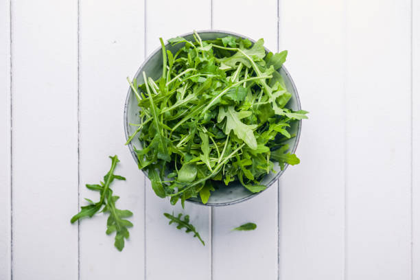 Bowl with fresh green salad arugula rucola Bowl with fresh green salad arugula rucola on a wooden Black or White background arugula stock pictures, royalty-free photos & images