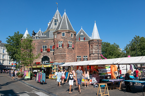 Amsterdam, The Netherlands - August 03, 2018: Nieuwmarkt square with medieval Waag building and people visiting a daily general goods market in the old centre of Amsterdam
