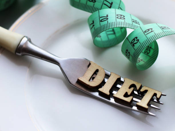 Empty white plate and fork, diet inscription in wooden letters