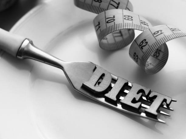 istock Empty white plate and fork, diet inscription in wooden letters 1078518146