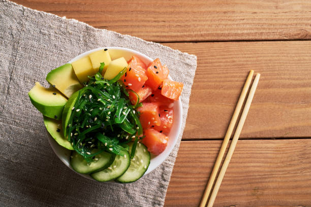 istock bowl with salmon, avocado, chuka salad, mango, sprinkled with white and black sesame with chopsticks and soy sauce, linen napkin tablecloth on wooden background top view 1078518944