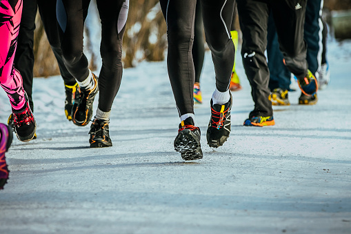 legs group of runners running on winter trail road in snow