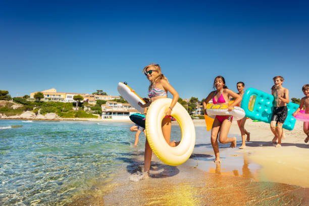 istock Teens running into the sea with swimming tools 1078526226