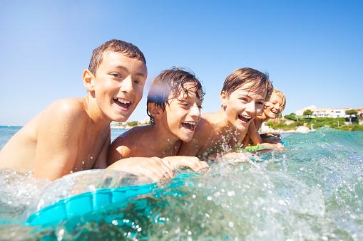 Close-up portrait of cheerful teenage boys swimming in the sea on air mattress in summer