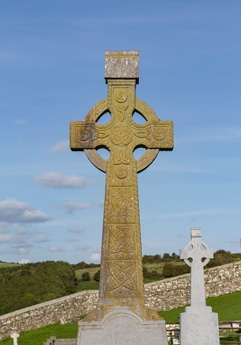 In rural Ireland, graves are often marked with Celtic crosses. This one in Western Ireland shows signs of age and is carved with trefoil knots and celtic knots.