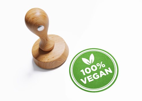 Wooden 100 % vegan stamp on white background. Horizontal composition with copy space. High angle view.