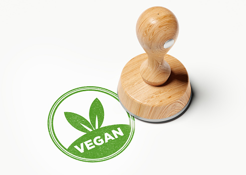 Wooden vegan stamp on white background. Horizontal composition with copy space. High angle view.