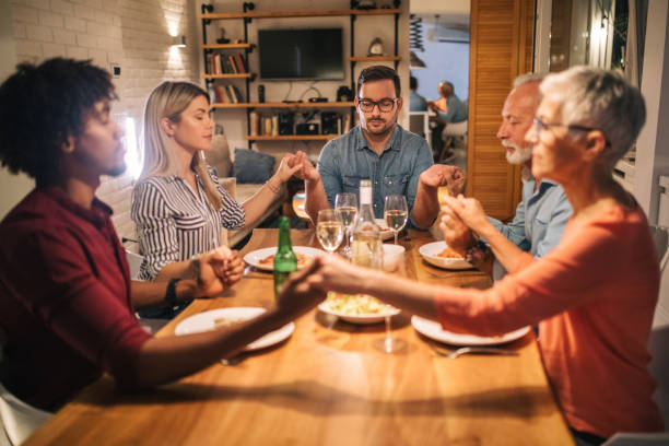 istock Family and friends praying before dinner while holding hands 1078543512