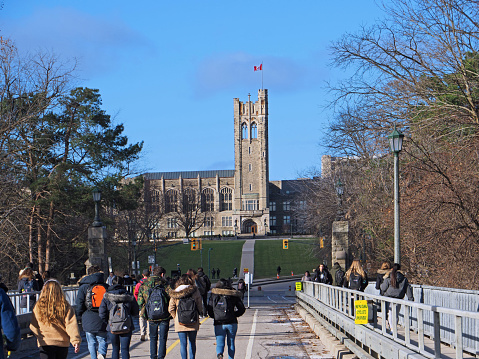 London, Ontario, Canada - December 4, 2018:  Students cross the bridge to enter the campus, walking toward the gothic tower of University College at Ontario's Western University.