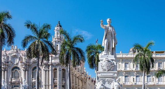 Havana, Cuba. 20th November 2018. Palm trees and statue of José Martí in central Havana with ornate buildings behind on a sunny day.