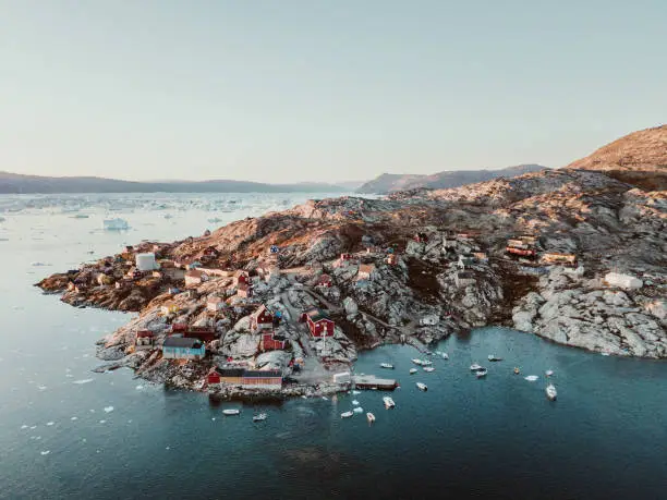 This panorama photo shows a fishing village in the bay of Tasiilaq in East Greenland from above at sunset.