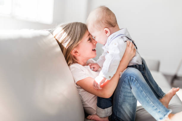 little sister with her baby brother. toddler kid family with children at home. - material data sheets imagens e fotografias de stock