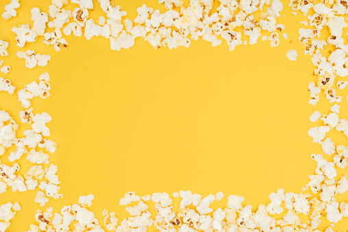 frame made of fresh tasty popcorn isolated on yellow