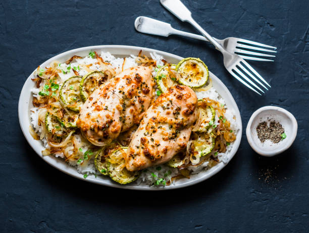 servido o almoço - dijon cozido de frango com arroz, abobrinhas e cebolas fritas, sobre um fundo escuro, vista superior - greek cuisine chicken grilled grilled chicken - fotografias e filmes do acervo