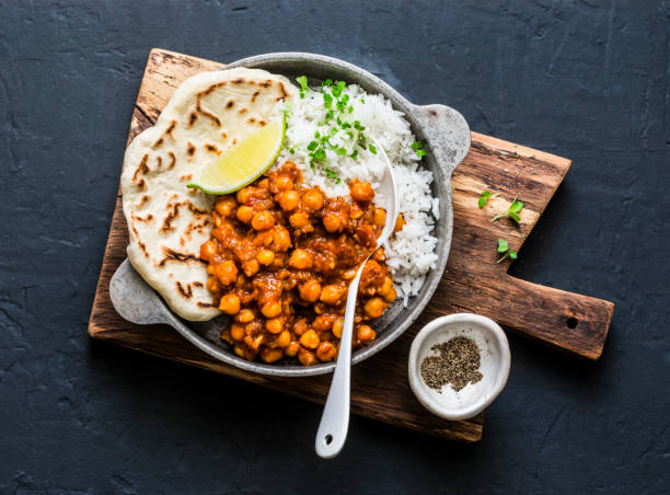 garbanzos picantes indios al curry con arroz y naan pan en cacerola en fondo oscuro, vista superior. comida sana vegetariana sabrosa - comida hindú fotos fotografías e imágenes de stock
