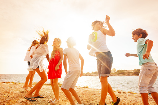 Portrait of happy teenage friends dancing and having fun during beach party in summer