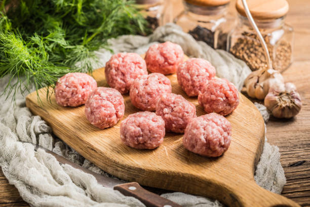 Raw meatballs on the wooden cutting board. Raw meatballs on the wooden cutting board. Small depth of field. polish culture photos stock pictures, royalty-free photos & images