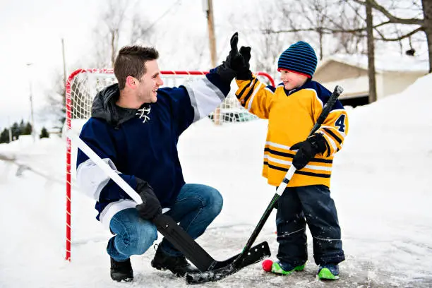 A nice Father and son have fun playing hockey
