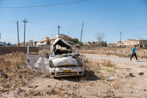 Destruction after ISIS in Qaraqosh, Iraq A young man walks past a destroyed vehicle in the predominately Christian town of Qaraqosh, Iraq, months after the Iraqi army pushed out ISIS fighters who had occupied the town for two years. islamic state stock pictures, royalty-free photos & images