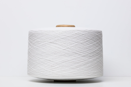 A tightly wound spool of white nylon thread with visible texture on white background