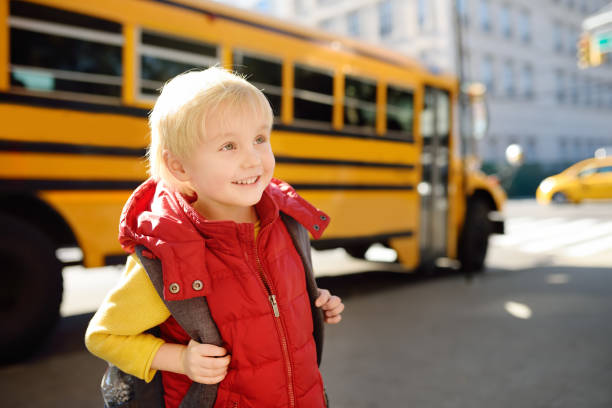 istock Pupil with schoolbag with yellow school bus on background 1078627586