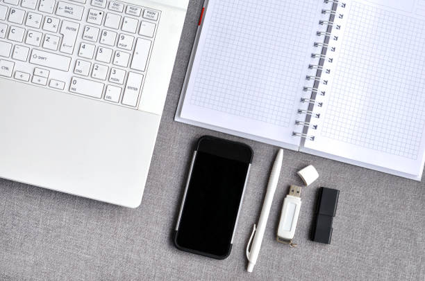 istock High above view of office workplace with mobile phone and laptop close up computer keyboard with notebook, pen and usb flash on grey desk. Working blogging desk table concept 1078661082