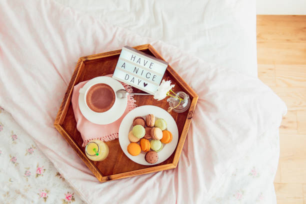 istock Top view Breakfast in bed with Have a nice day text on lighted box. Cup of coffee, juice, macaroons, flower in vase on wooden tray. Good morning mood. Hospitality, care, service concept. Copy space. 1078667696