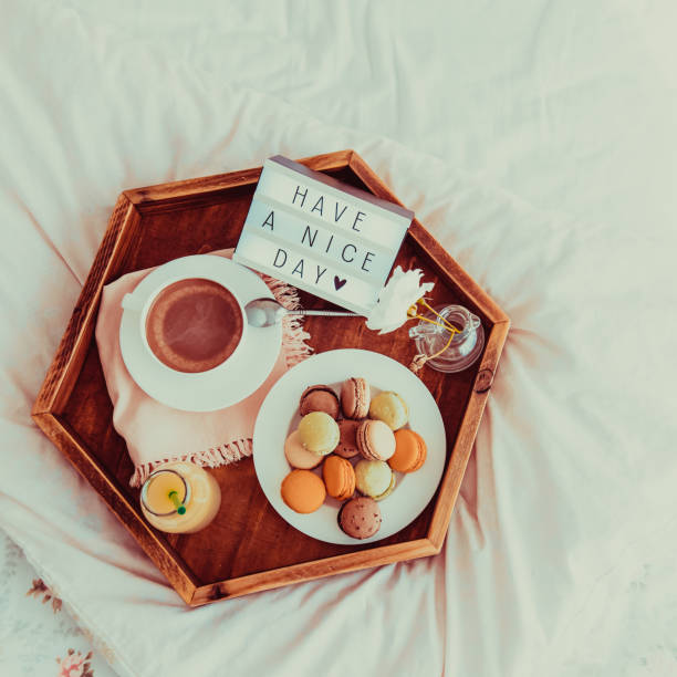 istock Top view Breakfast in bed with Have a nice day text on lighted box. Cup of coffee, juice, macaroons, flower on wooden tray. Good morning mood. Hospitality, care, service concept. Square. Copy space. 1078667704