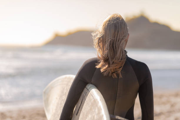 istock A female surfer walking along the beach 1078714376