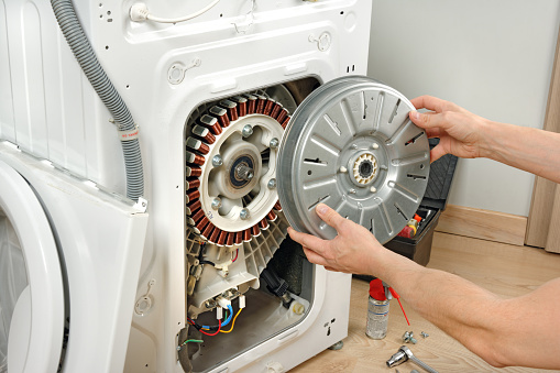 A service technician repairs a damaged washing machine