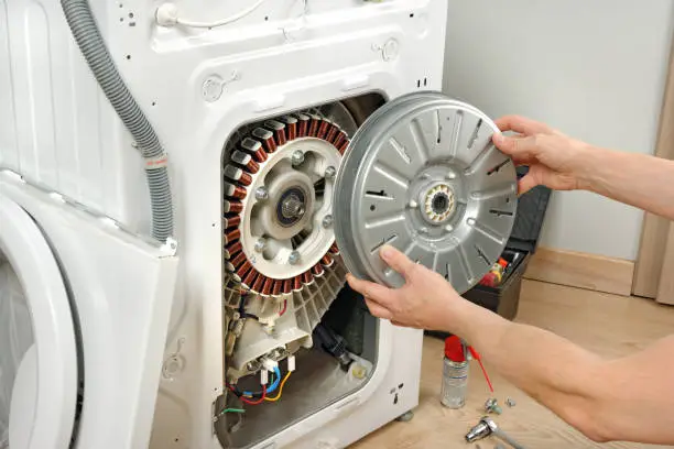 A service technician repairs a damaged washing machine