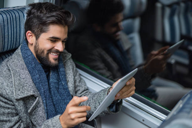 istock Happy young businessman using a digital tablet while traveling home by train late at night. 1078836170