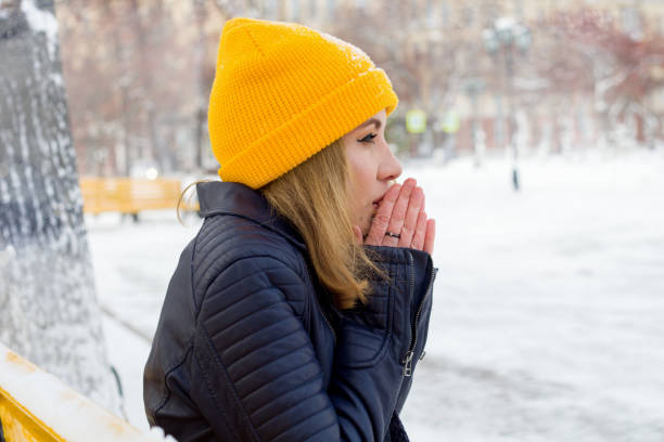 beautiful young woman warming her hands on the street - snow winter bench park imagens e fotografias de stock