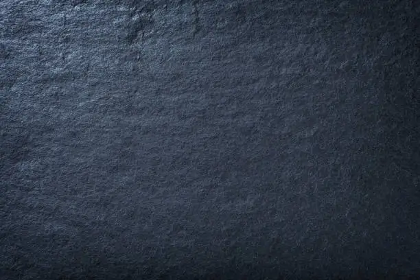 Navy blue background of natural slate. Texture of stone closeup. Graphite backdrop macro
