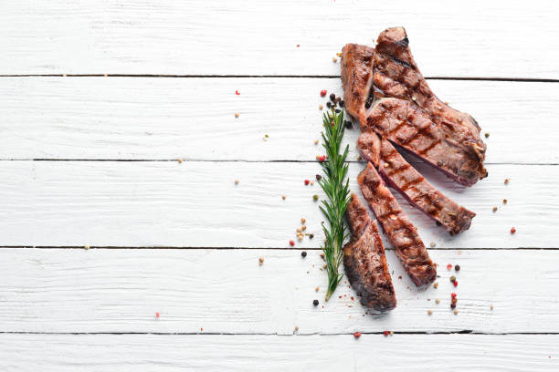 istock Veal steak on a bone on a white wooden background. Free space for your text. Top view. 1078909916