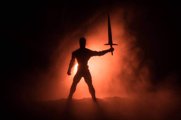 Medieval battle scene. Silhouette of warrior on dark toned foggy background. Night scene. Selective focus