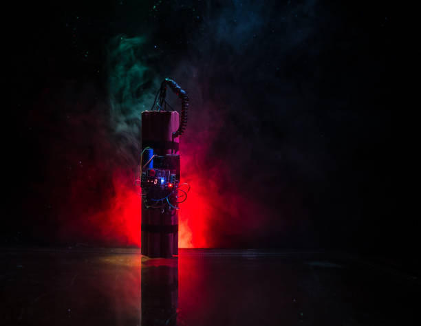 istock Image of a time bomb against dark background. Timer counting down to detonation illuminated in a shaft light shining through the darkness, 1078911132