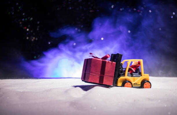istock Miniature Gift Box by Forklift Machine on snow ,Determined Image for Christmas Holiday and Happy New Year Gift Celebration concept. 1078915926