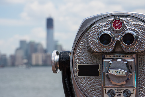 Image of a lookout binocular with a blurry cityscape in the background