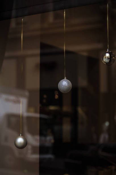 istock Three Christmas ornament holiday balls hanging by gold thread in a window with a reflection of a city scene 1078943072
