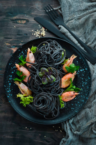 istock Black pasta with shrimps on a black plate. Top view. On a black background. Free copy space. 1078949810