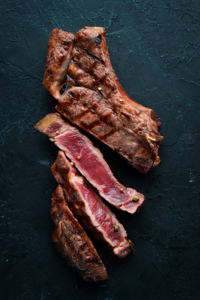 istock Veal steak on a bone on a black background. Free space for your text. Top view. 1078952666