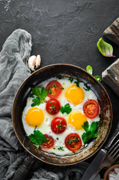 istock Eggs with tomatoes and greens in a frying pan. 1078954006