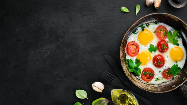 istock Eggs with tomatoes and greens in a frying pan. 1078954218