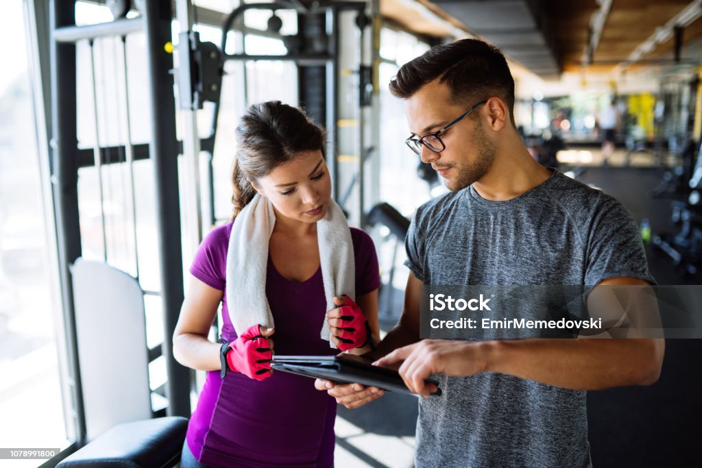 Frau und Personal Trainer machen Übungsplan im Fitnessstudio - Lizenzfrei Fitnesstraining Stock-Foto