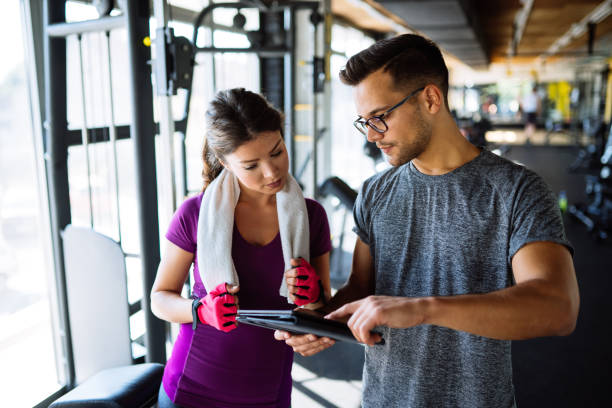 Woman and personal trainer making exercise plan in gym Woman and personal trainer making exercise plan in gym fitness trainer stock pictures, royalty-free photos & images