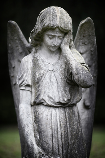 Guardian angel statue forlorn in graveyard